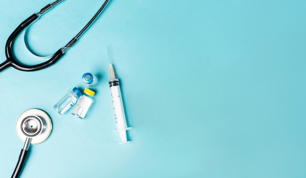 Image of stethoscope, vaccine tube, man injecting on blue background