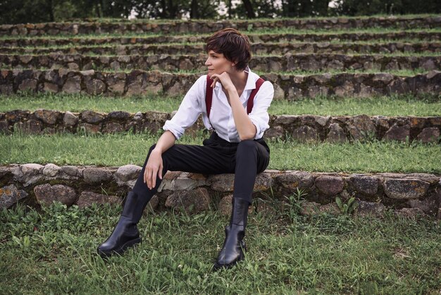 Image of a stylish beautiful woman in a white shirt black trousers and red suspenders The concept of style and fashion