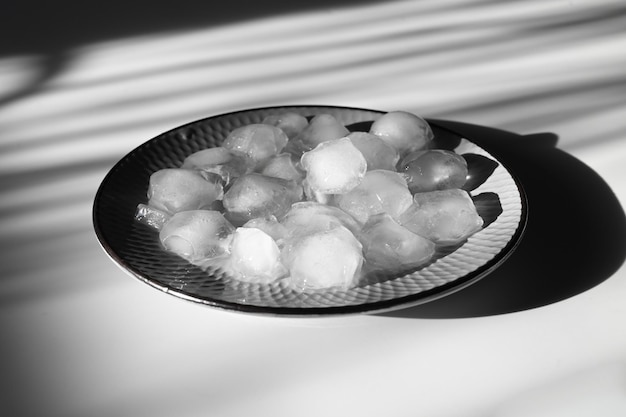 Изображение стильной серой тарелки со льдом и тенью от солнца на заднем плане Стильный фон со льдом и жесткой тенью
