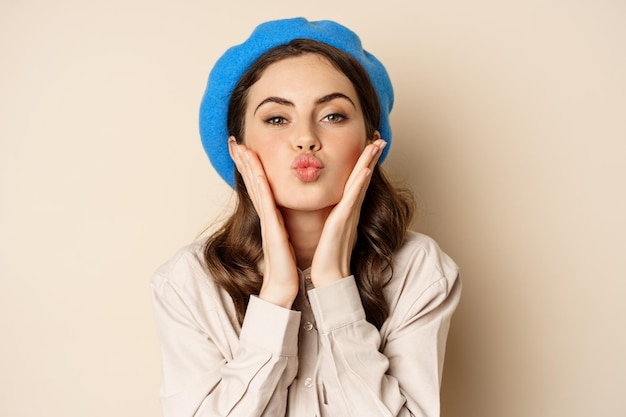 Image of stylish modern girl with makeup clear glowing skin pucker lips kissing face standing over b...