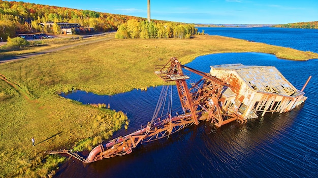 Image of Sunken dredge aerial shot with a river and silo in the background