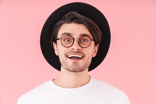 Image of surprised cheerful man wearing eyeglasses and black hat smiling