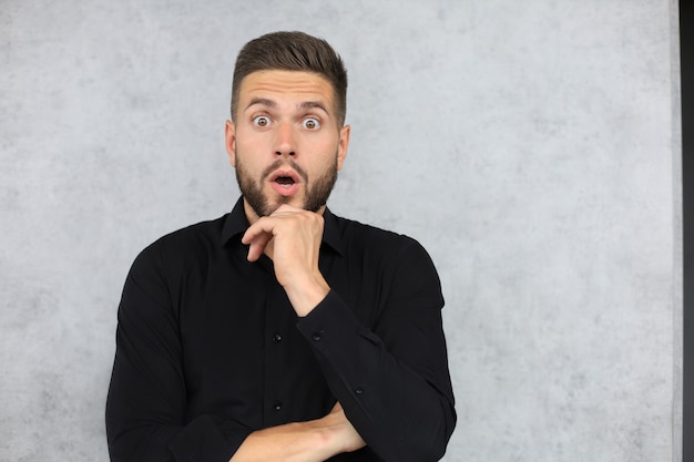 Image of surprised young man wearing formal clothes looking at camera with open mouth isolated over gray background.