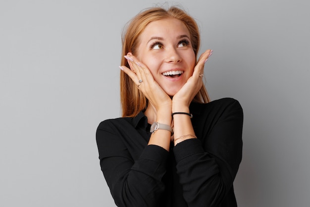 Image of thinking young woman standing over a gray background