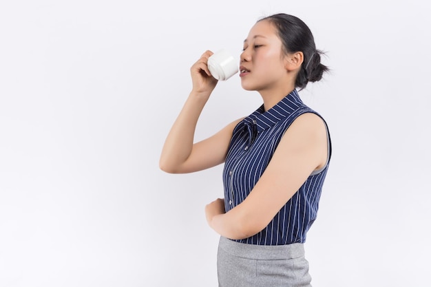 Image of thoughtful cheerful lady worker standing in office holding cup of coffee Look at window