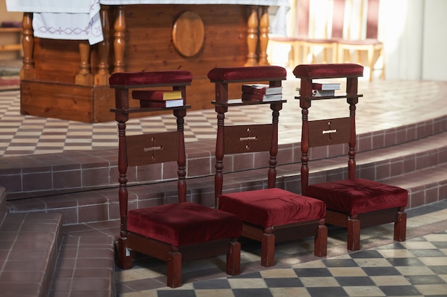 Photo image of three chairs standing in a row in empty catholic church