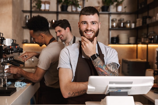 Image of three happy coffee men colleagues in cafe bar working indoors.