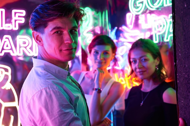 Photo image of two beautiful women and one man in an amusement park in a room with neon light entertainment concept