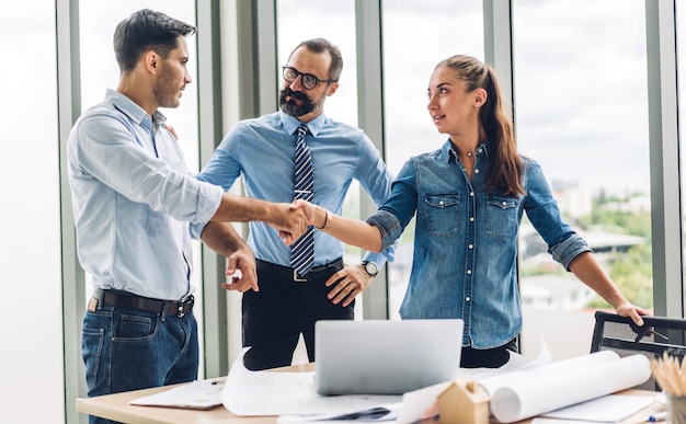 Image two business partners successful handshake together in front of casual businessman in modern office