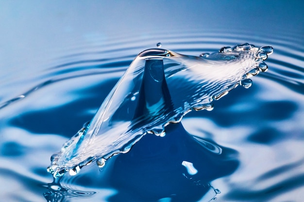 Image of Two water drops colliding on blue water with ripples