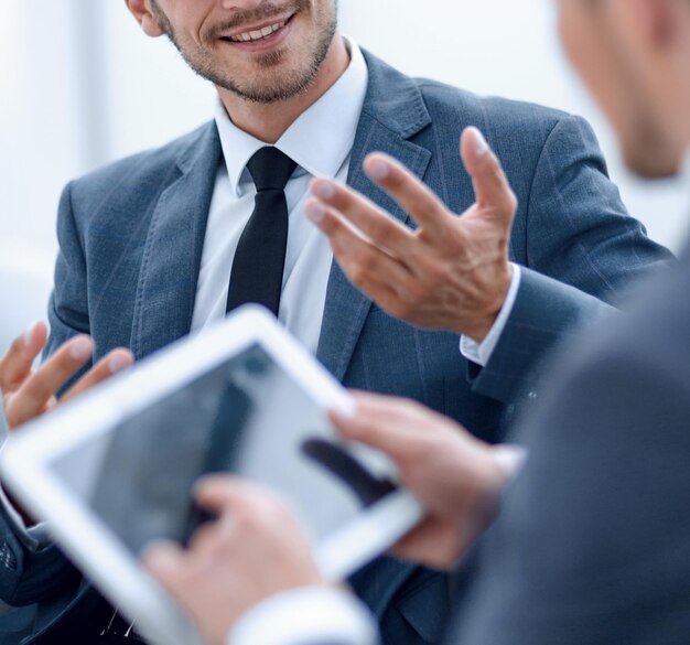 Image of two young businessmen using touchpad at meeting