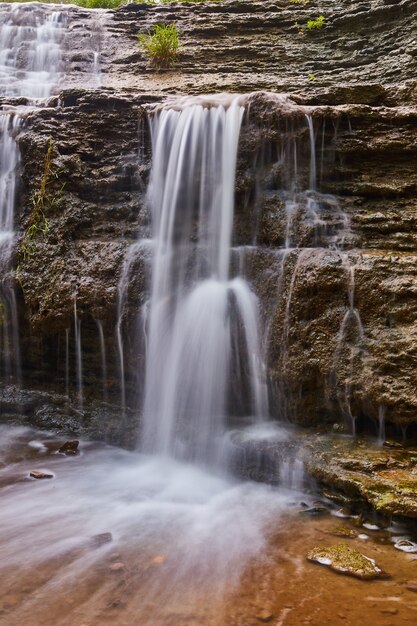 Image of Vertical waterfall detail over dark brown rock cliffs