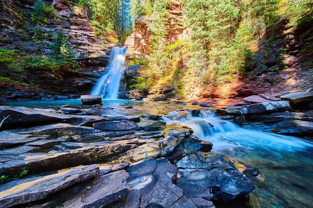 岩の層と峡谷の鮮やかな青い水と滝の画像