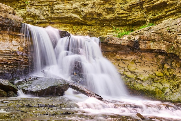 Image of Waterfalls over rocky cliffs onto boulders and log