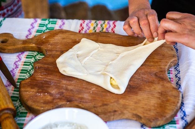 image with the hands of a lady cooking traditional Romanian fried pies with cheese