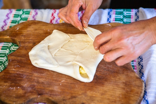 치즈와 함께 전통적인 루마니아 튀긴 파이를 요리하는 여성의 손으로 이미지