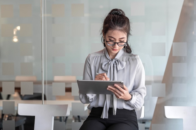 Photo image of a woman holding tablet sitting and waiting in the office job interview