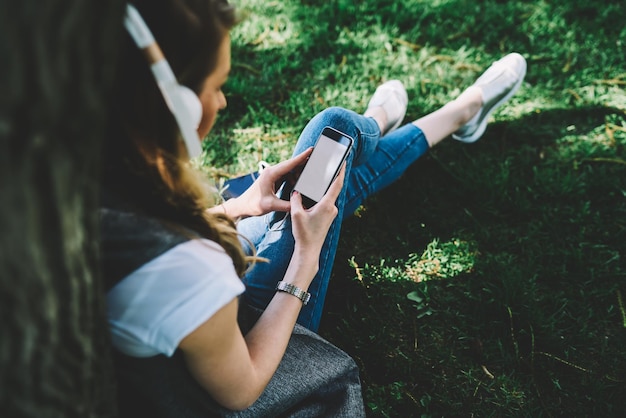 Image of woman looking for cool music in popular websites using\
modern telephone and internet