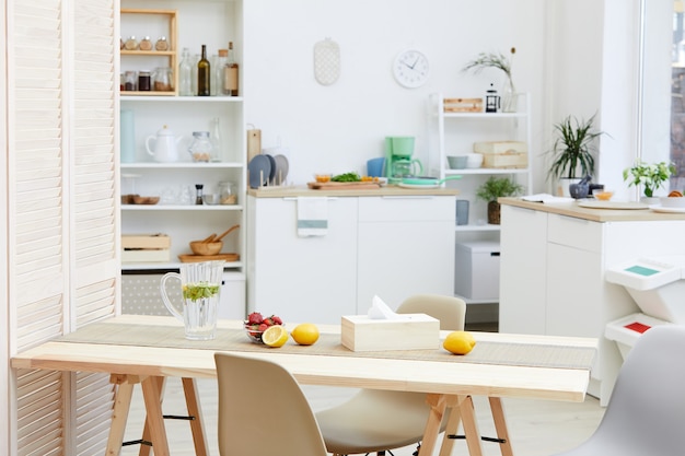 Immagine del tavolo da cucina in legno con limonata e frutta su di esso nella cucina domestica