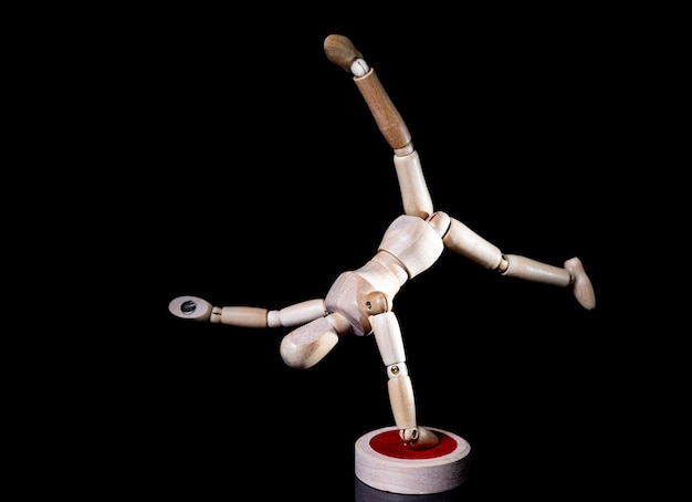 Image of wooden manikin on black background poses different posing