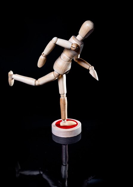 Image of wooden manikin on black background poses different posing