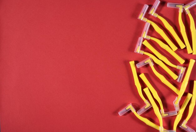 Image of yellow interdental brushes on a red background in the right side of the frame