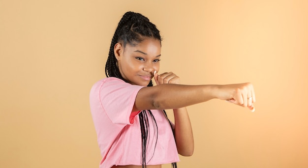 Image of a young African boxer throws punch, strong woman, yellow background