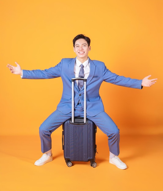 Image of young Asian business man holding suitcase on background