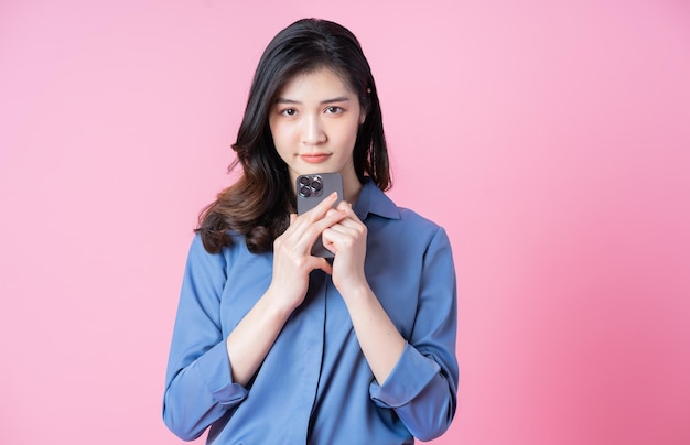 Image of young Asian business woman using smartphone on pink background