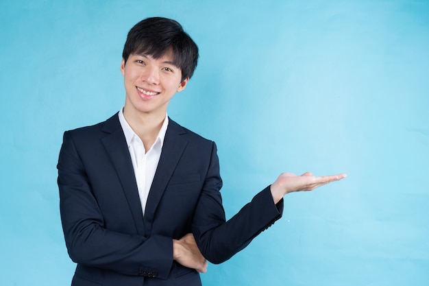 Image of young Asian businessman wearing a suit on a blue background