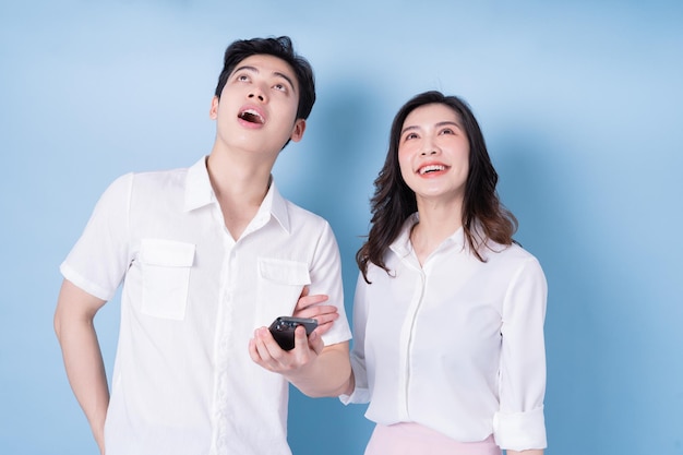 Image of young Asian couple using smartphone on blue background