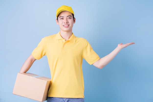 Image of young Asian delivery man on blue background