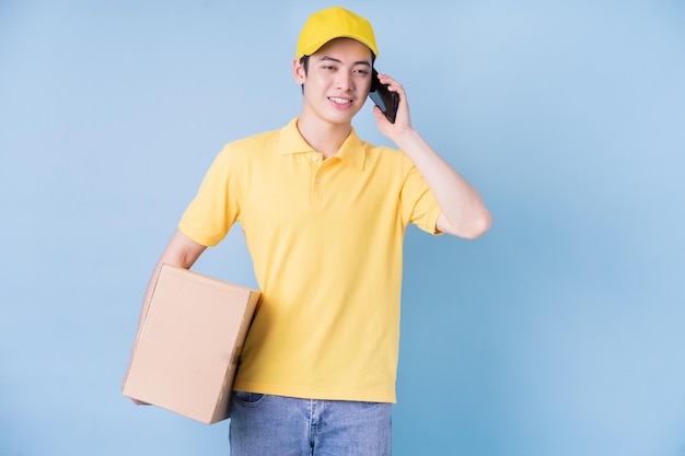 Image of young Asian delivery man on blue background