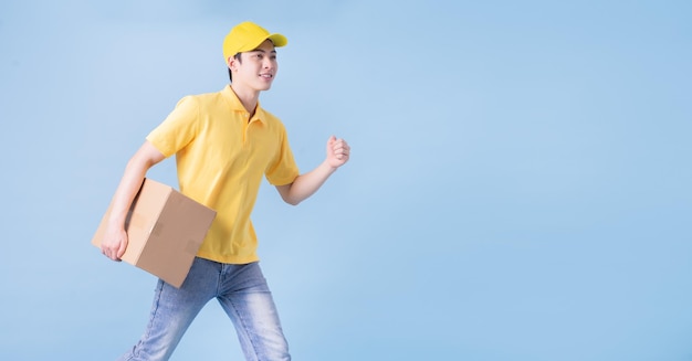 Image of young Asian delivery man on blue background