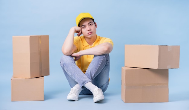 Image of young Asian delivery man on blue background