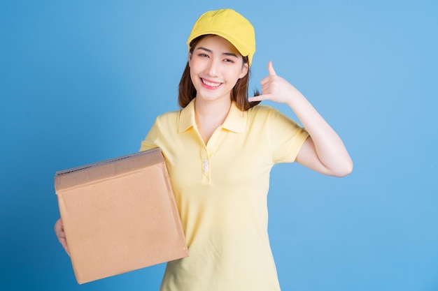 Image of young Asian delivery woman on blue background