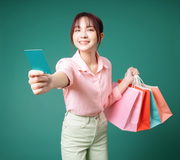 Image of young Asian girl holding shopping bag on background