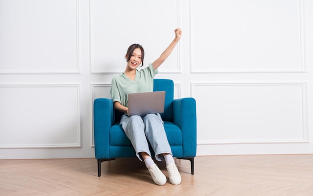 Image of young Asian girl sitting on sofa at home