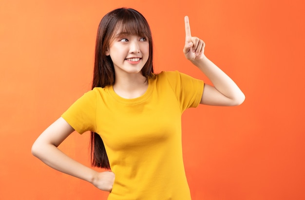 Image of young Asian girl wearing yellow t-shirt on orange