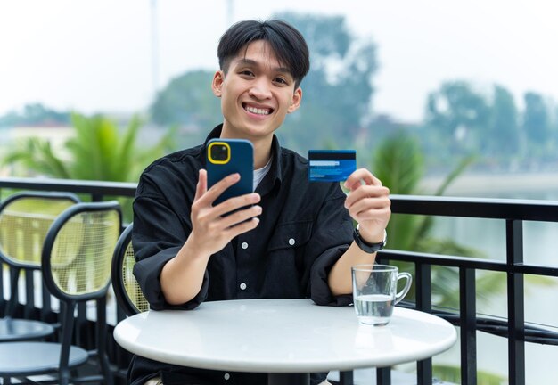 Image of young Asian male using phone at a cafe