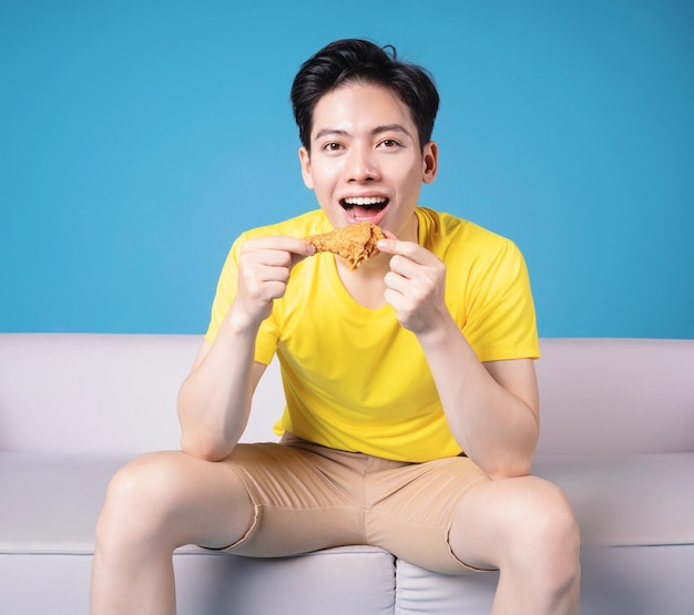 Image of young Asian man sitting on sofa