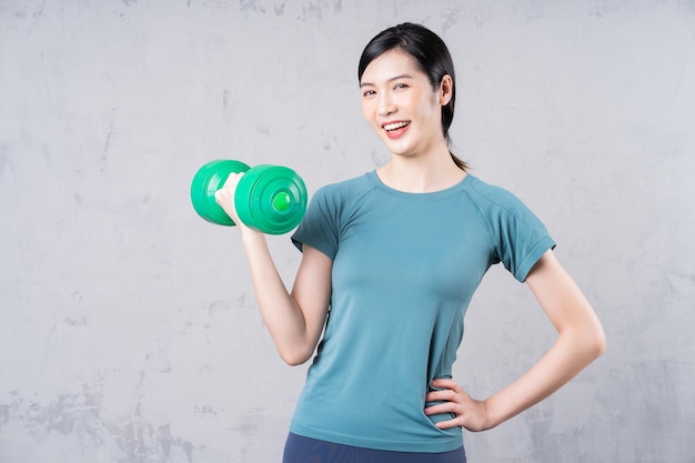 Image of young Asian woman holding dumbbell