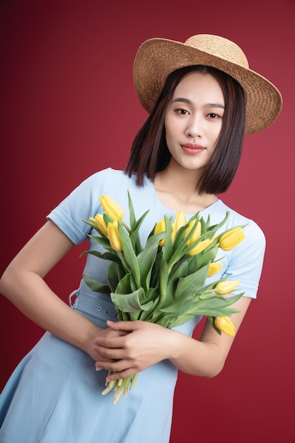 Image of young Asian woman holding tulips flowers on background