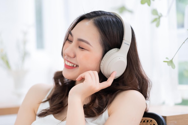 Image of young Asian woman listening music at home in the morning