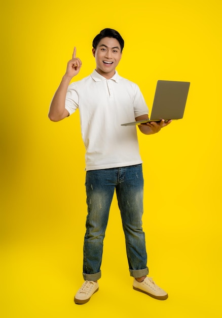 Image of young businessman using laptop on yellow background