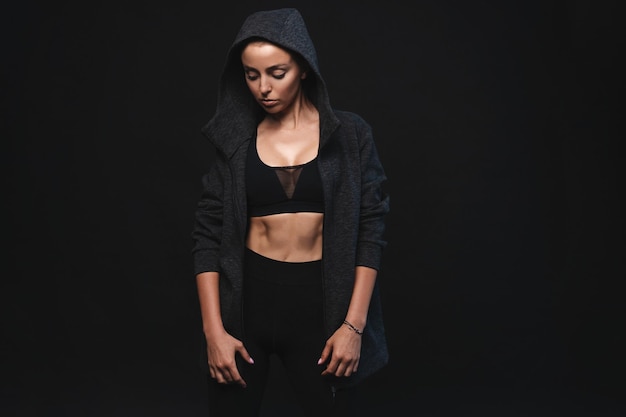 Image of young female model in sportswear standing on black background with copyspace