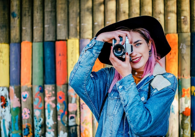 カラフルな壁の前に立っている若い女性写真家のイメージ。