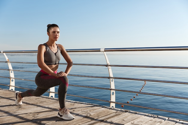 Image of young fitness woman workout at the seaside promende