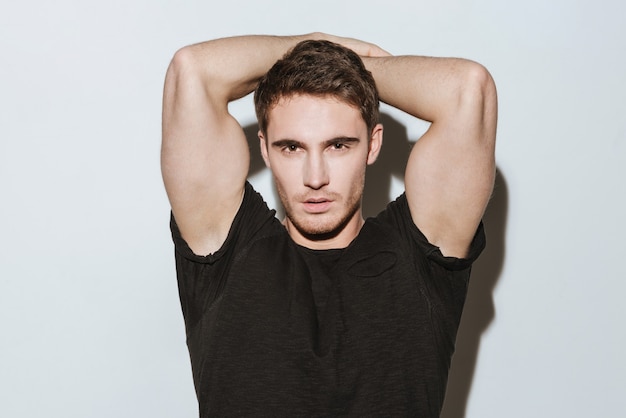 Image of young handsome strong man dressed in black t-shirt standing over white background.