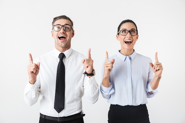 Image of young happy business colleagues couple isolated over white wall pointing.